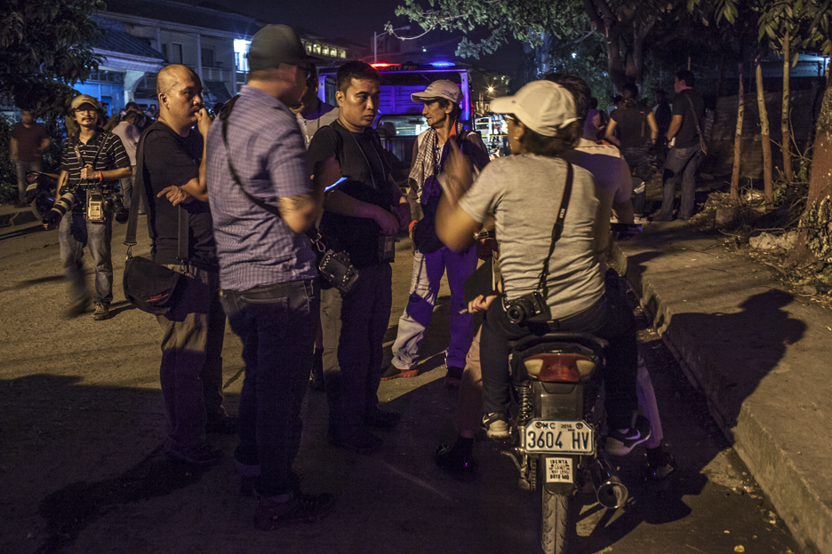 Fellow photographers huddle near a crime scene, planning the next move